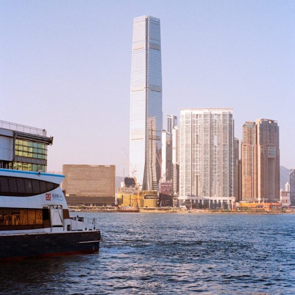 Ferry boat sails past hong kong skyline with skyscrapers.